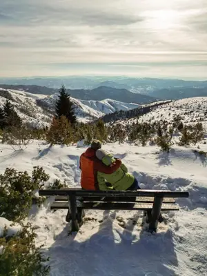 two people sitting on a bench in the snow at Alpine Retreat Čupino Sokače in Kopaonik