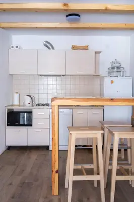 a kitchen with a wooden table and two stools at Alpine Retreat Čupino Sokače in Kopaonik