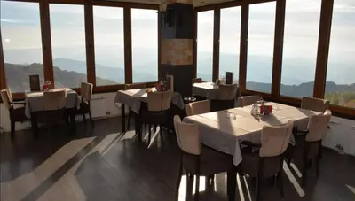 a dining room with tables and chairs and large windows at Panorama apartments in Milmari Resort in Kopaonik
