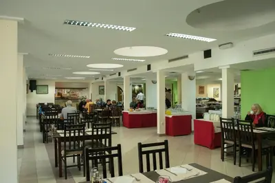 a dining room with people sitting at tables in a restaurant at Hotel Radan Prolom Banja in Prolomska Banja