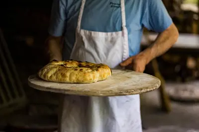 a person holding a plate with a pastry on it at Hotel Radan Prolom Banja in Prolomska Banja