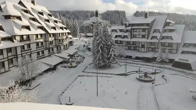 a snow covered street in a town with buildings at Apartments Mozaik in Kopaonik