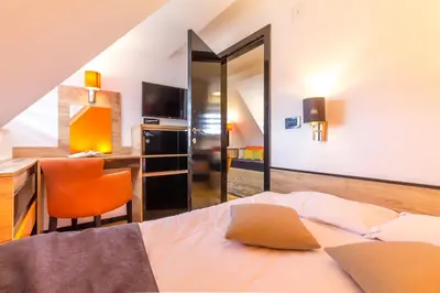 a bedroom with a bed and a desk and a kitchen at Apartments Mozaik in Kopaonik