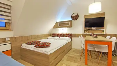 a small bedroom with a bed and a table at Apartments Mozaik in Kopaonik