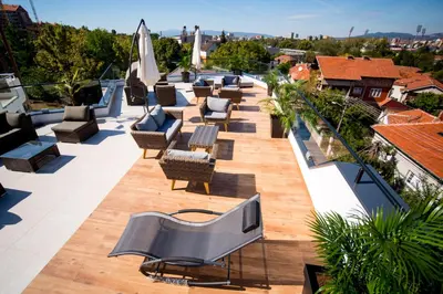 a rooftop patio with chairs and a television on a roof at Apel Luxury in Niš