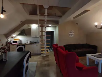 a living room with red chairs and a kitchen at Apartment Jelena in Kopaonik