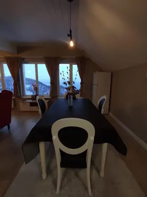 a dining room with a table and chairs and windows at Apartment Jelena in Kopaonik