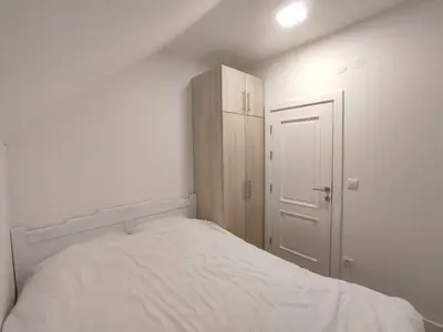 a small bedroom with a white bed and a cabinet at Apartment Jelena in Kopaonik