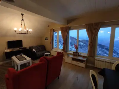 a living room with a couch and chairs and windows at Apartment Jelena in Kopaonik