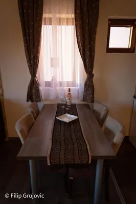 a dining room table with a bottle of wine on it at Apartment G6 in Kopaonik