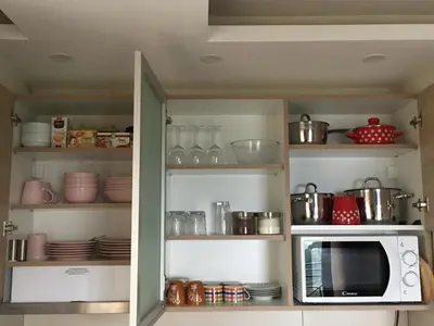 a kitchen with a microwave and dishes on shelves at Apartment G6 in Kopaonik