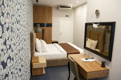 a bedroom with a bed and a table and a mirror at Hotel Crystal Light in Niš