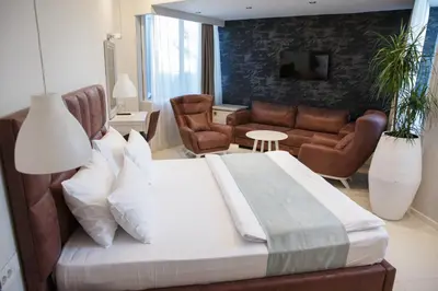a bedroom with a large bed and a living room at Hotel Crystal Light in Niš