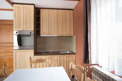 a kitchen with wooden cabinets and a table and a window at Vila Tisa in Kopaonik