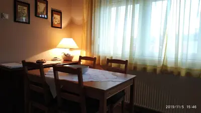a dining room table and chairs with a lamp and a window at Apartman Rada in Pirot