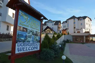 a sign in the grass next to some buildings at Apartman Mia Milmari in Kopaonik
