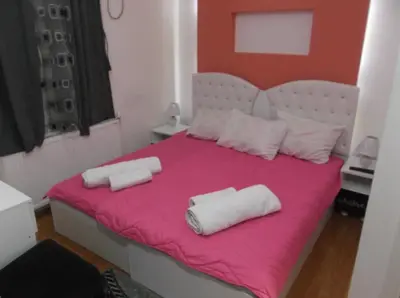 a bedroom with a pink bed with two white towels on it at Prenociste Bojan 017 in Vranje