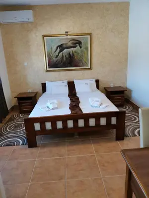 a large bed in a room with a picture on the wall at JOKSIM Rooms&Restaurant in Kuršumlija