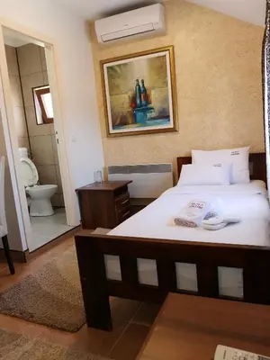 a bedroom with a bed and a bathroom with a toilet at JOKSIM Rooms&Restaurant in Kuršumlija
