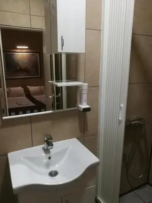 a bathroom with a white sink and a mirror at JOKSIM Rooms&Restaurant in Kuršumlija