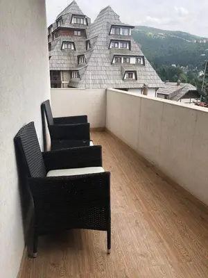 two chairs on a balcony with a view of a building at Apartment Elvir in Kopaonik