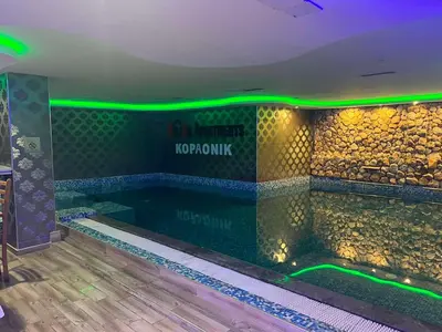 a swimming pool in a room with green lights at Apartment Elvir in Kopaonik