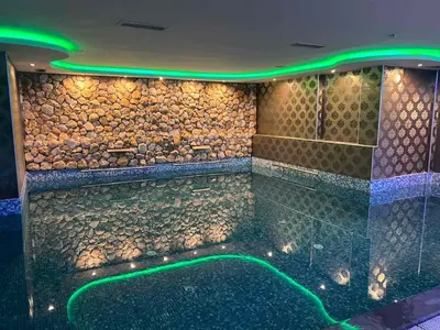 a swimming pool with a rock wall and green lights at Apartment Elvir in Kopaonik