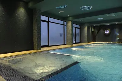 a large swimming pool in a room with windows at Sunny Kop Čardaci in Kopaonik