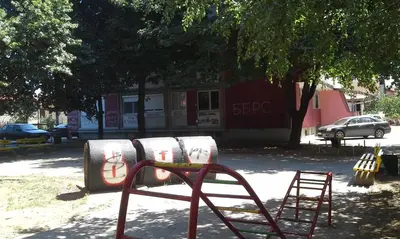a playground in front of a building with a tree at Studio Ema in Niš