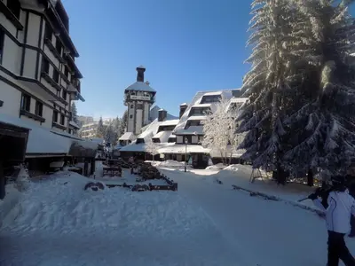 a snow covered street with a building and a clock tower at Apartment Ski Star Konaci in Kopaonik