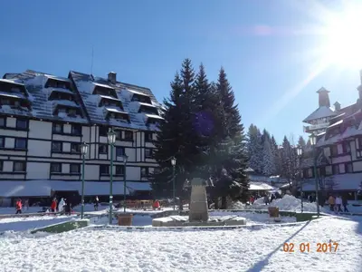 a building in the snow with a monument in front of it at Apartment Ski Star Konaci in Kopaonik