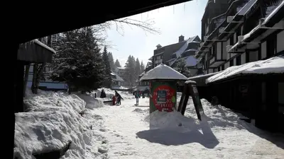 a street covered in snow with people walking down the street at Apartment Ski Star Konaci in Kopaonik