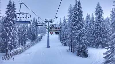 a ski lift with people riding on it in the snow at Apartments Zed Vila Zvoncica in Kopaonik