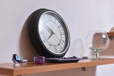 a clock sitting on a shelf next to a wine glass at MB Apartments in Jagodina