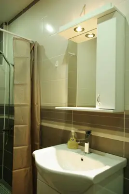 a bathroom with a sink and a mirror and a shower at Square Studio Apartment in Niš