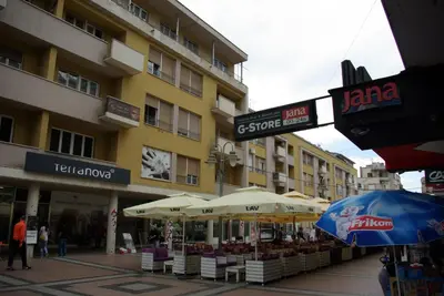 a building with umbrellas and tables in front of it at Square Studio Apartment in Niš