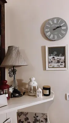 a clock on a wall next to a table with a lamp at Apartment Marija- Kopaonik centar in Kopaonik