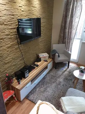 a living room with a flat screen tv on a brick wall at Apartment Marija- Kopaonik centar in Kopaonik
