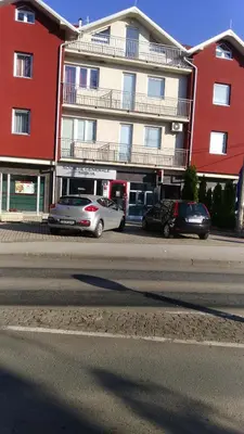 two cars parked in front of a large building at Apartmani Tamara in Vrnjačka Banja