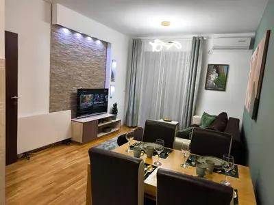 a living room with a dining table and a tv at Alex apartman in Vrnjačka Banja