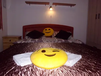 two smiley faces are sitting on a bed at Smiley Apartman in Vrnjačka Banja