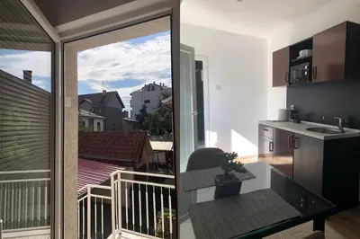 a kitchen and a balcony with a view of a city at Apartments Ivan in Niš
