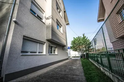an empty sidewalk next to a building with a fence at Apartments Ivan in Niš