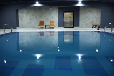 a swimming pool with two chairs and a table at Zepter Spa Wellness Hotel & Zepterme member of Zepter Hotels in Vrnjačka Banja