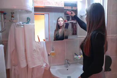 a woman standing in front of a bathroom mirror at Hotel Tehnograd in Kraljevo