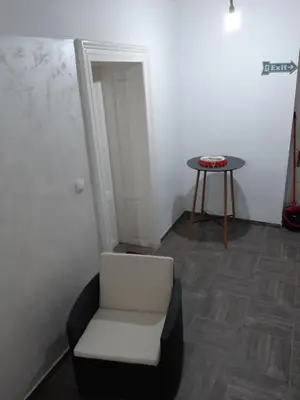 a room with a white chair and a table at Apartmani LolaNola in Vrnjačka Banja