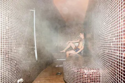 a woman is sitting on a wall in a shower at B&B Nataly 2 in Soko Banja