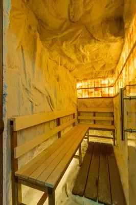 a wooden bench in a room with a rock wall at B&B Nataly 2 in Soko Banja