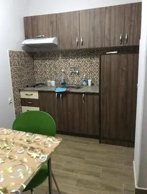 a kitchen with wooden cabinets and a table with a green chair at Apartments Zlatko in Soko Banja
