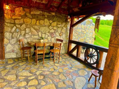 a stone house with a table and chairs and a window at Etno selo Stanojevic in Boljevac